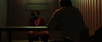 Movie still from “Sicario: Day of the Soldado” (2018), directed by Stefano Sollima – A man sitting in front of another man in a dark room; Medium shot, Over the shoulder angle