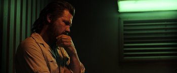 Movie still from “Sicario: Day of the Soldado” (2018), directed by Stefano Sollima – A man sitting in front of a green light; Close Up shot, Low angle
