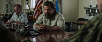 Movie still from “Sicario: Day of the Soldado” (2018), directed by Stefano Sollima – A man sitting at a table with a cup of coffee; Medium shot, Over the shoulder angle