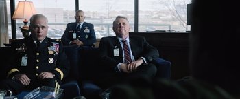 Movie still from “Sicario: Day of the Soldado” (2018), directed by Stefano Sollima – A man in a suit sitting in front of another man in a suit; Medium shot, Over the shoulder angle