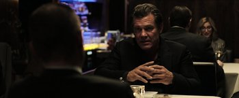 Movie still from “Sicario: Day of the Soldado” (2018), directed by Stefano Sollima – A man sitting at a table with another man in front of him; Medium shot, Over the shoulder angle