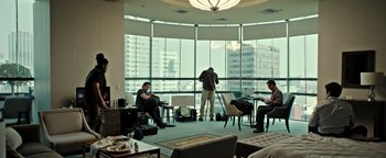 Movie still from “Sicario: Day of the Soldado” (2018), directed by Stefano Sollima – A group of people sitting in a room with a television set; Wide shot, Low angle