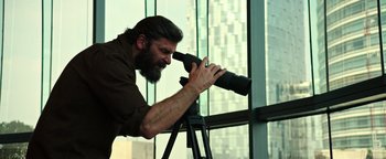 Movie still from “Sicario: Day of the Soldado” (2018), directed by Stefano Sollima – A man with a beard is taking a picture with a camera; Medium shot, Low angle