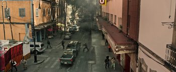 Movie still from “Sicario: Day of the Soldado” (2018), directed by Stefano Sollima – A group of people on a street with smoke coming from a building; Extreme Wide shot, High angle