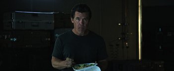 Movie still from “Sicario: Day of the Soldado” (2018), directed by Stefano Sollima – A man holding a plate of food in his hand; Medium shot, Over the shoulder angle