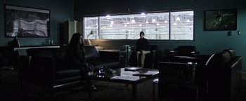 Movie still from “Sicario: Day of the Soldado” (2018), directed by Stefano Sollima – A man and a woman are sitting in a dark room; Wide shot, Over the shoulder angle