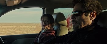 Movie still from “Sicario: Day of the Soldado” (2018), directed by Stefano Sollima – A woman sitting in the back seat of a car with blood coming out of her face; Medium shot, Over the shoulder angle