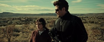 Movie still from “Sicario: Day of the Soldado” (2018), directed by Stefano Sollima – A man and a girl in a field with mountains in the background; Medium shot, Over the shoulder angle