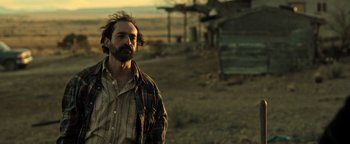 Movie still from “Sicario: Day of the Soldado” (2018), directed by Stefano Sollima – A man standing in a field near a building; Medium shot, Low angle