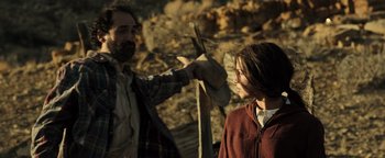 Movie still from “Sicario: Day of the Soldado” (2018), directed by Stefano Sollima – A man and a woman are holding a wooden stick; Medium shot, Over the shoulder angle