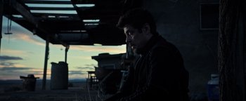 Movie still from “Sicario: Day of the Soldado” (2018), directed by Stefano Sollima – A man in a black jacket is looking at the sky; Medium shot, Over the shoulder angle