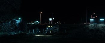Movie still from “Sicario: Day of the Soldado” (2018), directed by Stefano Sollima – A bus is parked on the side of the road at night; Extreme Wide shot, Low angle