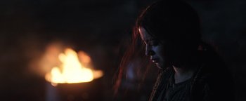 Movie still from “Sicario: Day of the Soldado” (2018), directed by Stefano Sollima – A woman with red hair is standing in front of a fire; Close Up shot, Over the shoulder angle
