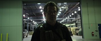 Movie still from “Sicario: Day of the Soldado” (2018), directed by Stefano Sollima – A man in a black shirt is standing in a warehouse; Medium shot, Low angle