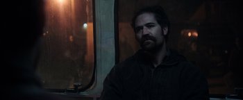 Movie still from “Sicario: Day of the Soldado” (2018), directed by Stefano Sollima – A man with a beard is looking out a window; Medium shot, Over the shoulder angle