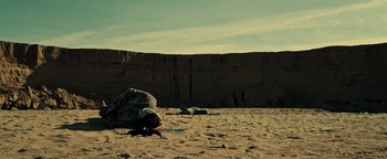 Movie still from “Sicario: Day of the Soldado” (2018), directed by Stefano Sollima – Two people laying in the sand near a cliff; Extreme Wide shot, Low angle