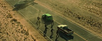Movie still from “Sicario: Day of the Soldado” (2018), directed by Stefano Sollima – An aerial view of a group of people trying to pull a car off the road; Extreme Wide shot, High angle
