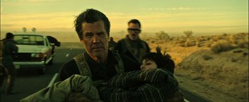Movie still from “Sicario: Day of the Soldado” (2018), directed by Stefano Sollima – A man holding a child in a field with another man; Medium shot, Low angle