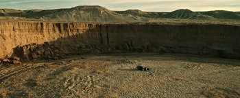 Movie still from “Sicario: Day of the Soldado” (2018), directed by Stefano Sollima – An animal laying on the ground in the middle of the desert; Extreme Wide shot, High angle