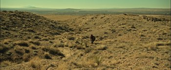 Movie still from “Sicario: Day of the Soldado” (2018), directed by Stefano Sollima – A person in a field of grass and dirt; Extreme Wide shot, High angle