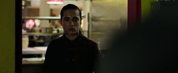 Movie still from “Sicario: Day of the Soldado” (2018), directed by Stefano Sollima – A man standing in a dark room looking at the camera; Close Up shot, Over the shoulder angle