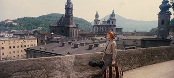 Movie still from “The Sound of Music” (1965), directed by Robert Wise – A woman walking on the roof of a building with luggage; Wide shot, High angle