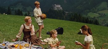 Movie still from “The Sound of Music” (1965), directed by Robert Wise – A group of people sitting in the grass on a hill; Wide shot, High angle
