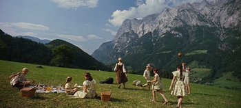 Movie still from “The Sound of Music” (1965), directed by Robert Wise – A group of people sitting in a field with mountains in the background; Extreme Wide shot, High angle