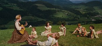 Movie still from “The Sound of Music” (1965), directed by Robert Wise – A group of children sitting on the grass in a field; Wide shot, High angle