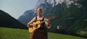 Movie still from “The Sound of Music” (1965), directed by Robert Wise – A woman sitting on the grass holding a guitar; Wide shot, Low angle