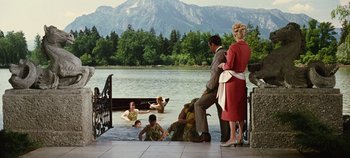 Movie still from “The Sound of Music” (1965), directed by Robert Wise – A group of people sitting on a dock near a body of water; Wide shot, High angle