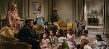 Movie still from “The Sound of Music” (1965), directed by Robert Wise – A group of people sitting in a living room; Wide shot, Over the shoulder angle