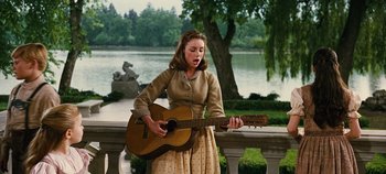 Movie still from “The Sound of Music” (1965), directed by Robert Wise – A woman in a brown dress is playing a guitar; Medium shot, Low angle