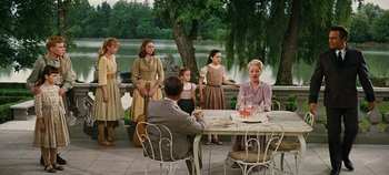 Movie still from “The Sound of Music” (1965), directed by Robert Wise – A group of people standing around a table; Wide shot, Low angle
