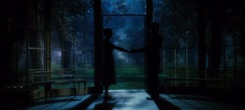 A man and a woman shaking hands in front of a window