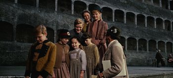Movie still from “The Sound of Music” (1965), directed by Robert Wise – A group of people standing next to each other in front of a building; Medium shot, High angle