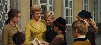 Movie still from “The Sound of Music” (1965), directed by Robert Wise – Two women and a boy are looking at a book; Medium shot, Over the shoulder angle