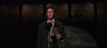 Movie still from “The Sound of Music” (1965), directed by Robert Wise – A man holding a guitar in front of a microphone; Medium shot, Low angle
