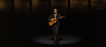 Movie still from “The Sound of Music” (1965), directed by Robert Wise – A man standing on a stage with a guitar; Wide shot, Low angle