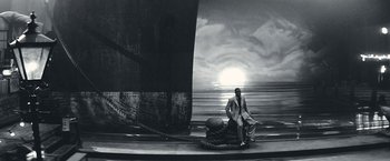 A black and white photo of a man sitting on a boat