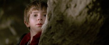 Movie still from “The Spiderwick Chronicles” (2008), directed by Mark Waters – A young boy looking at the camera from behind a tree; Close Up shot, Low angle