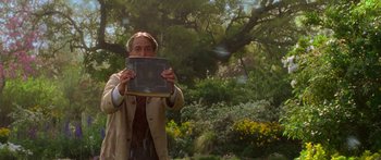 Movie still from “The Spiderwick Chronicles” (2008), directed by Mark Waters – A man holding a book in front of his face in a garden; Medium shot, Over the shoulder angle