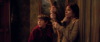 Movie still from “The Spiderwick Chronicles” (2008), directed by Mark Waters – A woman and a young boy holding a wooden stick; Medium shot, High angle