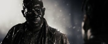 Movie still from “The Spirit” (2008), directed by Frank Miller – A man in a black jacket is covered in black paint; Close Up shot, Low angle