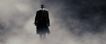 Movie still from “The Spirit” (2008), directed by Frank Miller – A man in a black coat and hat standing in the fog; Wide shot, Low angle