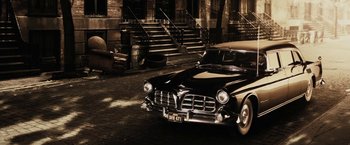 Movie still from “The Spirit” (2008), directed by Frank Miller – An old car parked on the side of the street; Wide shot, High angle