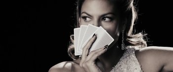 Movie still from “The Spirit” (2008), directed by Frank Miller – A beautiful woman holding four playing cards in front of her face; Close Up shot, Overhead angle