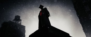 Movie still from “The Spirit” (2008), directed by Frank Miller – A man standing on top of a building in the dark; Medium shot, Low angle