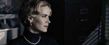 Movie still from “The Spirit” (2008), directed by Frank Miller – A woman in a black shirt and a pearl necklace looking to her left; Close Up shot, Over the shoulder angle