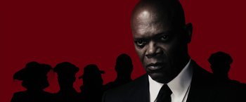 Movie still from “The Spirit” (2008), directed by Frank Miller – A man in a suit and tie with a red background; Close Up shot, Low angle